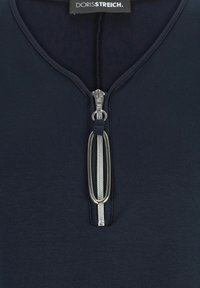 Navyblaues Zip-Up-Oberteil mit runden Kragen und einem silbernen Reißverschluss, der einen verlängerten Zugtab hat und aus einem glatten, weichen Material besteht.