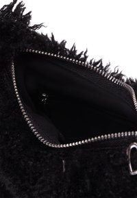 Geantă de mână fuzzy neagră, cu o suprafață texturată, fermoar argintiu și un interior spațios căptușit cu țesătură neagră.
