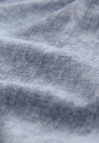 Tessuto di denim azzurro chiaro, con una consistenza morbida e leggero allungamento; mostra sottili variazioni di tonalità e trama, creando un aspetto uniforme.
