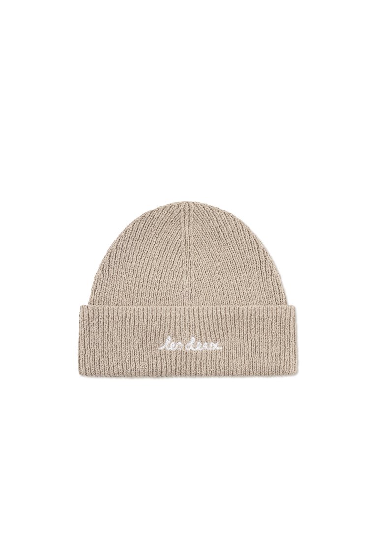 Beige stickad mössa med ribbat mönster och uppvikt kant. Har vit broderad text framtill.