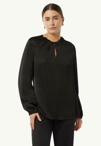 Schwarze Satinbluse mit einem Schlüssellochausschnitt, sanften Rüschen am Kragen und langen Ärmeln mit elastischen Bündchen. Glatte, glänzende Textur.