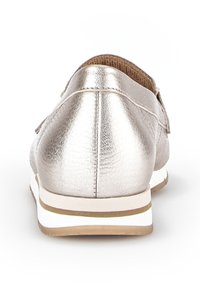Metallisch zilveren instap-schoen met een gladde textuur, ronde neus en contrasterende witte tussenzool. Voorzien van een kleine decoratieve band aan de achterkant.