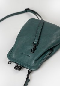 Borsa a tracolla in pelle teal con forma strutturata, dotata di zip superiore, accessori in metallo nero e tracolla regolabile.