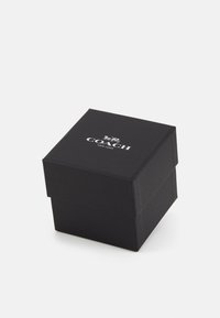 Schwarze quadratische Box aus strukturiertem Pappe. Hat ein silbernes Logo auf der Oberseite. Schließt mit einer Klappe und hat scharfe, klare Kanten.