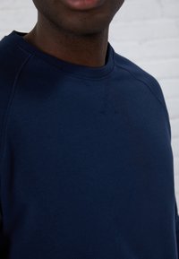 Felpa blu navy con colletto a girocollo, in morbido cotone e dettagli di cucitura a vista. La vestibilità è comoda, con un design minimalista.