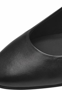 Ballerine plate noire avec un bout rond, une surface extérieure lisse et une coupe basse. L'intérieur présente une finition douce et mate.