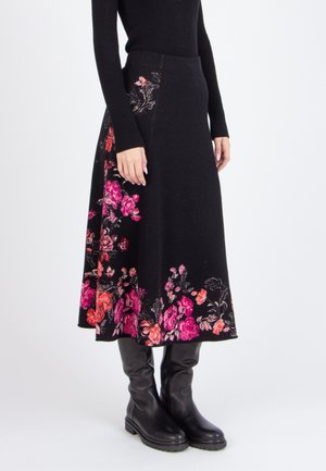 Gonna nera a fiori con ricami rosa e arancioni lungo l'orlo, realizzata in un tessuto texturizzato. Indossata con stivali neri al ginocchio.