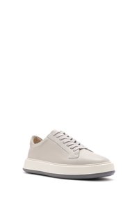 Baskets en cuir gris clair avec une texture lisse, bout rond, lacets plats et semelle en caoutchouc blanche. Détails de couture subtils sur les côtés.