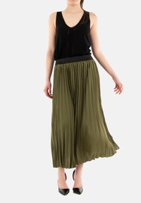 Haut sans manches noir associé à une jupe maxi plissée vert olive dotée d'une taille élastique noire et d'une texture lisse et fluide.