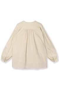 Blusa beige chiaro con maniche lunghe a sbuffo, dettaglio arricciato sulla schiena e scollatura rotonda, realizzata in tessuto morbido e leggero.