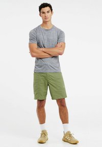 Sivi atletski majica s kratkim rukavima, zeleni šorts s dva prednja džepa, bež tenisice s teksturiranim potplatima i bijele ankletske čarape.