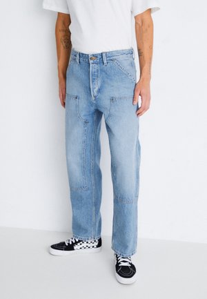 Lyseblå denimjeans med en løs pasform, der har kontrasterende syninger, frontlommer og en cropped kant. Båret med sort-hvide sneakers.