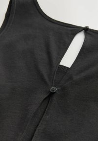 Čierny bavlnený tank top s výstrihom do oválu a bočným zapínaním na gombíky. Má rozdelený zadný dizajn pre pridanie detailu. Hladký povrch.
