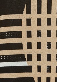 Textil mit einem sandfarbenen Grund und markanten schwarz-weißen Streifen, quadratischen Mustern und akzentuiert mit silbernen Punkten, die ein geometrisches Design erzeugen.