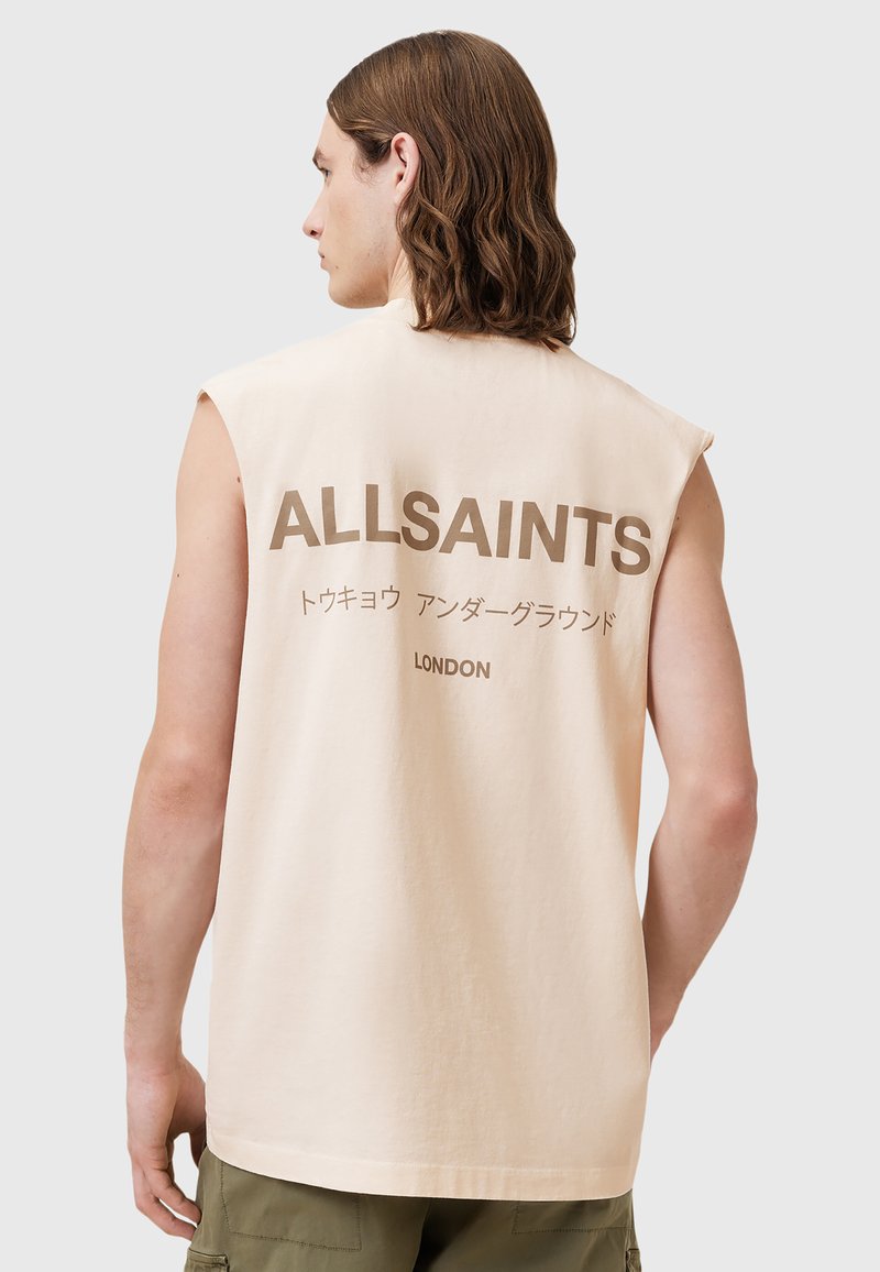 Ermeløs beige bomulls tanktopp med "ALLSAINTS" trykt i mørkebrunt på ryggen, med tilleggstekst på japansk og "LONDON."