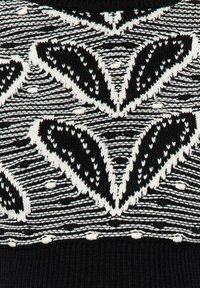 Tissu tricoté noir et blanc avec un motif géométrique comprenant des chevrons et des formes semblables à des feuilles en rangées alternées.