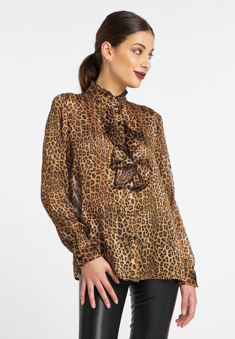 Blus i leopardmönster med volanghalsringning, långa ärmar och knappstängning. Tillverkad i lätt material, har svarta accenter.