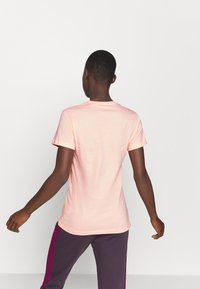 Camiseta de manga corta rosa claro hecha de algodón suave, con un escote redondo y un diseño ajustado, vista desde la parte de atrás.