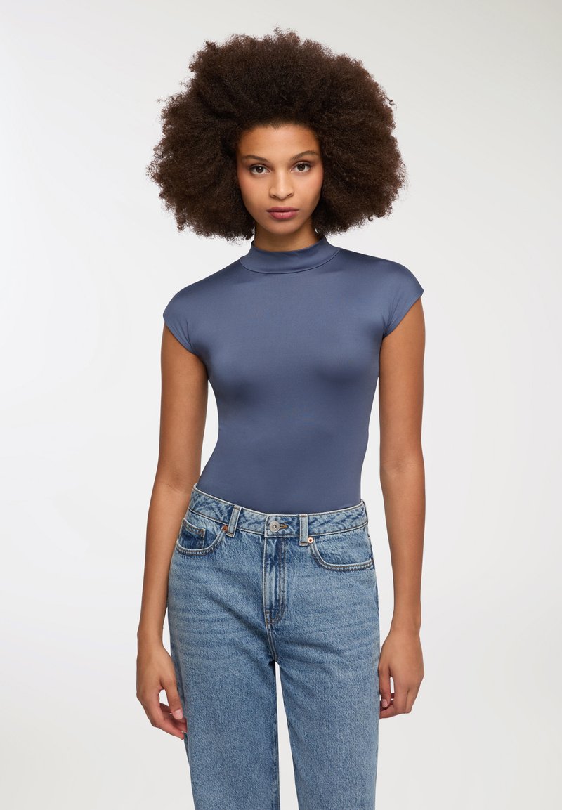 Granatowy, dopasowany bodysuit z wysokim dekoltem i krótkimi rękawami, połączony z jasnoniebieskimi jeansami z wysokim stanem z zapięciem na guzik i zamek.