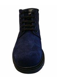 Zapato de ante azul marino con cordones negros, punta redonda y costuras en contraste. Suela de goma con leve elevación y superficie texturizada.