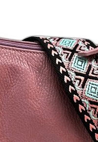 Roze leren handtas met een gestructureerd oppervlak, een ritssluiting en een patroonriem in zwart, mintgroen en roze geometrische ontwerpen.