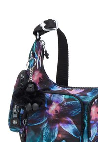 Floral print shoulder bag in black and vibrant blue, featuring a zippered pocket and a fuzzy black gorilla charm attached to the strap.
