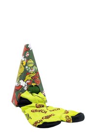 Calzini gialli luminosi con testo "Grinch" e una zona nera sulla punta, esposti in una scatola di cartone triangolare verde con grafiche festive.