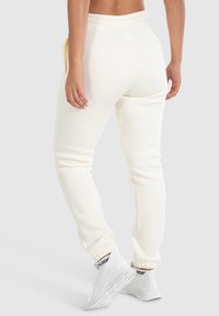Joggers color crema hechos de tela suave, con una cinturilla elástica, bolsillos laterales y puños ajustados en los tobillos.