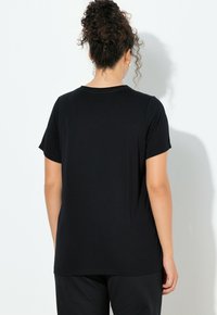 Camiseta negra de manga corta con cuello redondo. Tejido liso con un ajuste relajado, diseño sencillo y sin adornos visibles.