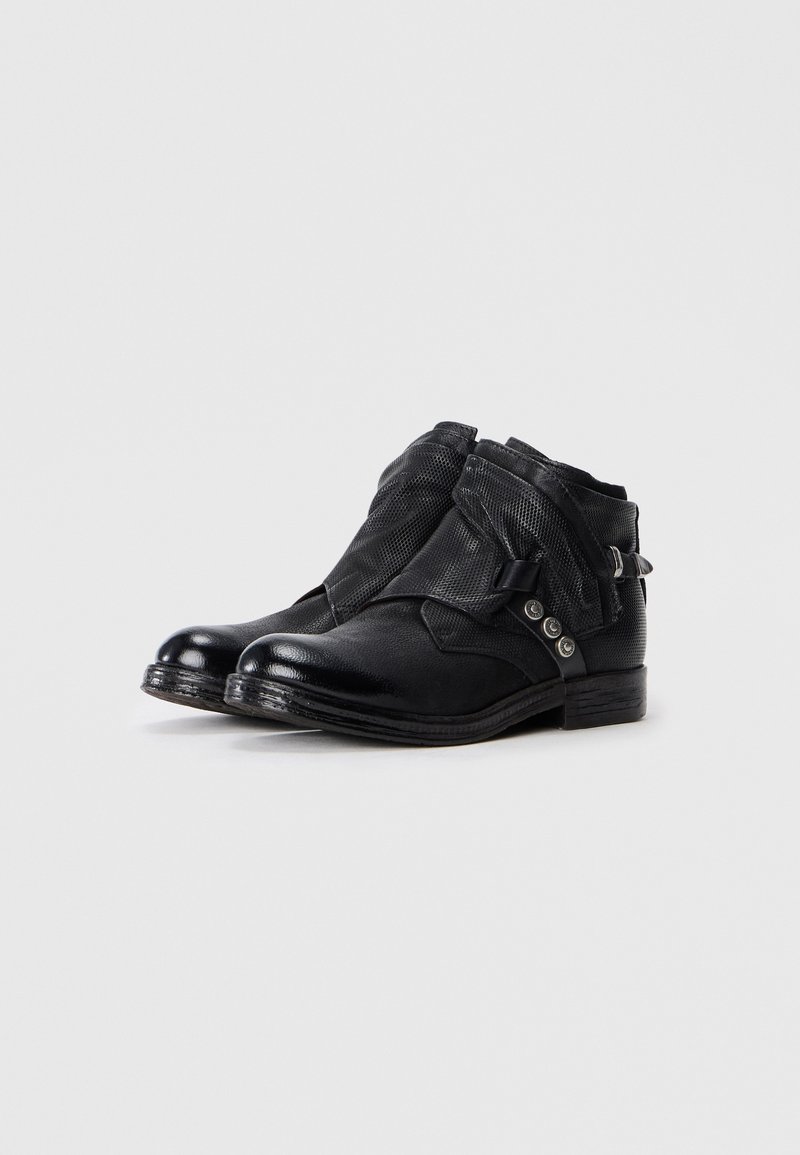 Botas negras hasta el tobillo hechas de cuero texturizado con un detalle de malla trenzada. Presenta un hebilla lateral y tres botones decorativos.