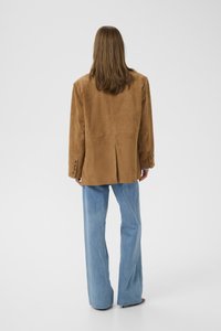 Brown suede blazer with a single vent, single-button closure, and four-button cuffs. Paired with light blue wide-leg jeans.