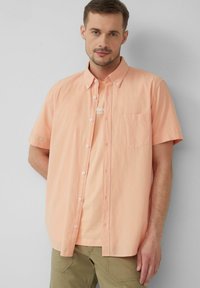 Korte mouwen, overhemd met knopen in lichtperzik, met een borstzak en een gestructureerde stof. Draag het over een eenvoudig lichtperzikkleurig T-shirt.