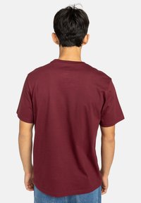 Camiseta de algodón burdeos con mangas cortas y cuello redondo, vista desde la parte de atrás, con una textura suave y un ajuste relajado.