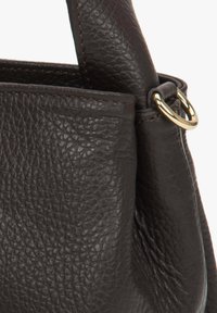 Brązowa torebka skórzana o teksturze, charakteryzująca się usztywnionym kształtem, widocznymi przeszyciami oraz złotym akcentem w postaci metalowego pierścienia na pasku.