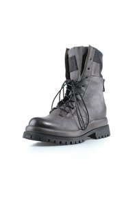 Botte de combat en cuir gris avec lacets noirs, fermeture éclair latérale partiellement ouverte et semelle épaisse crantée sur fond blanc.