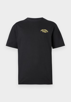Melnā īso piedurkņu kokvilnas t-kreklā ar dzelteno tekstu "FRANKS PIES" augšējā kreisajā krūtī.