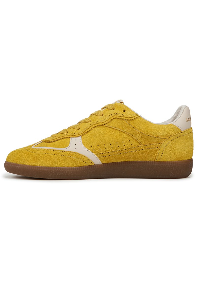 Sneaker giallo in suede con un elegante accento in pelle beige, caratterizzato da una punta arrotondata, lacci piatti, dettagli laterali perforati e una suola in gomma.
