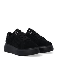 Une paire de baskets plates-formes en suede noir avec des semelles en caoutchouc épaisses et des œillets en métal sur fond blanc.