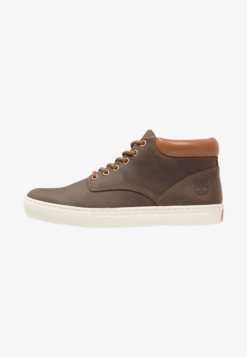 Baskets montantes en cuir marron avec col matelassé beige, lacets marron, semelle épaisse blanche et logo embossé sur le côté du talon.