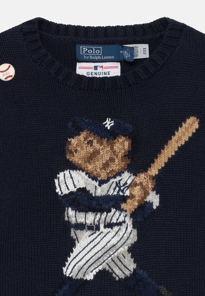 Tengerészeti kötött pulóver, amelyen egy baseball egyenruhát viselő medve látható, aki ütőt tart. Bordás nyak és egy kis baseball kitűző részlet a vállon.