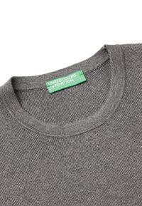 Grauer Rippstrickpullover mit rundem Ausschnitt. Das Etikett trägt die Aufschrift "UNITED COLORS OF BENETTON" auf grünem Hintergrund. Weiche Textur, lässiges Design.