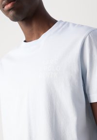 Světle modré bavlněné tričko s kulatým výstřihem. Na hrudi má decentní, vytlačené logo "MARC O'POLO DENIM". Krátké rukávy.