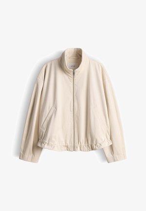 Hellbeige Reißverschlussjacke mit Stehkragen, langen Ärmeln, elastischem Saum und zwei schrägen Vorderseitentaschen, die vor weißem Hintergrund hängt.