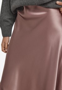 Satin midi nederdel i støvet rosa med en glat, skinnende tekstur. Figurformet talje med en flydende silhuet, kombineret med en grå sweaterdetalje.