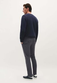 Marine crewneck sweater, grå slim-fit bukser, grå sneakers. Stoffet ser blødt ud, minimal detalje, ensfarvede og afslappet design.