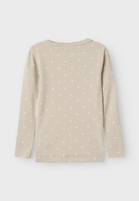 Pitkähihaisessa beige ribbikankaasta valmistetussa paidassa on pieniä valkoisia sydänkuvioita, pyöreä kaula-aukko ja tavalliset hihansuut. Pehmeä rakenne, rento muotoilu.