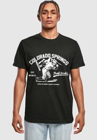 Mustapaitainen t-paita, jossa on valkoinen grafiikka baseball-pelaajasta ja tekstit "Colorado Springs" ja "Park Fields". Puuvillamateriaalia.