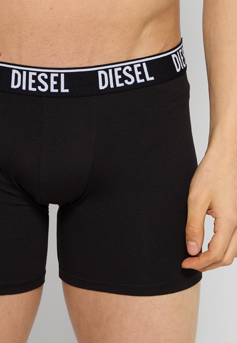 Black boxer shorts made of soft fabric, featuring an elastic waistband with "DIESEL" logo in white. Close-fitting design, minimal seams.