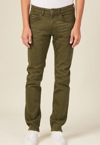 Jeans verdes oliva con un corte slim, que cuentan con cinco bolsillos, trabillas para cinturón, cierre de botón y un sutil desgastado en la tela.