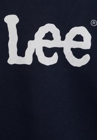 Granatowa bawełna z dużym, stylizowanym białym logo "Lee", o lekko teksturowanej powierzchni. Brak dodatkowych wzorów lub dekoracji.